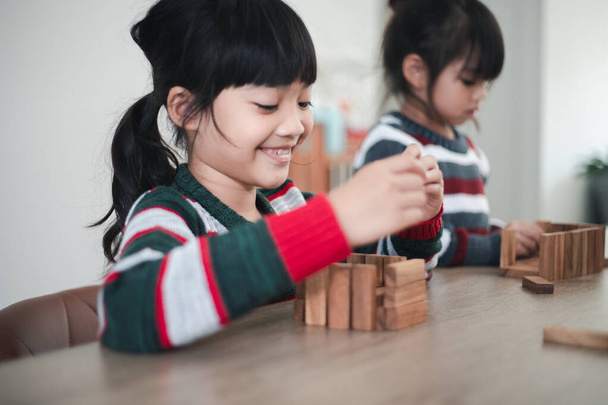 Cheerful Asian girl playing with wooden building blocks. Having fun and learning creativity. smart kid concept. - Photo, image