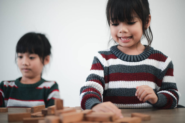 Cheerful Asian girl playing with wooden building blocks. Having fun and learning creativity. smart kid concept. - Zdjęcie, obraz