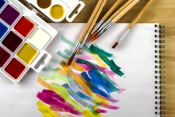 watercolor paints and brushes on a white sheet with color samples. High quality photo - Фото, зображення