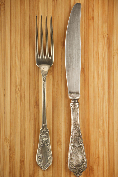 Vintage fork and knife on wooden chopping board - Fotó, kép
