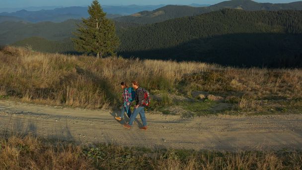 Drone tourists backpacks walking mountains path talking against green hills - Fotoğraf, Görsel