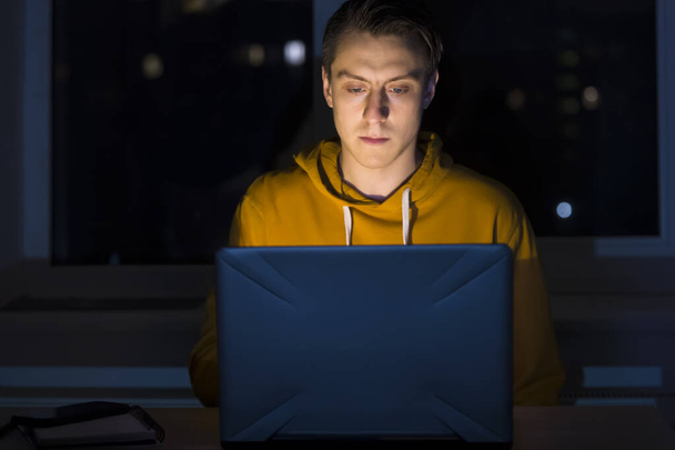 Человек работает над ноутбуком ночью. - Фото, изображение