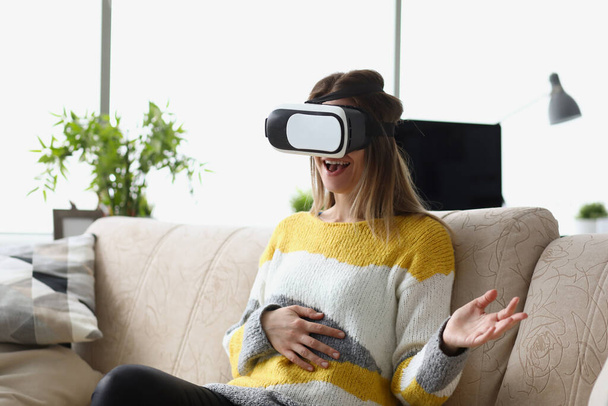 Female sit on sofa wear vr glasses modern device, enjoy spare time in imagination world - Photo, Image