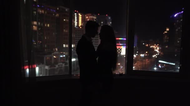 Giovane coppia romantica trascorrere del tempo insieme a casa di notte. Gli amanti si baciano appassionatamente vicino alla finestra. Due amanti che si abbracciano a San Valentino - Filmati, video