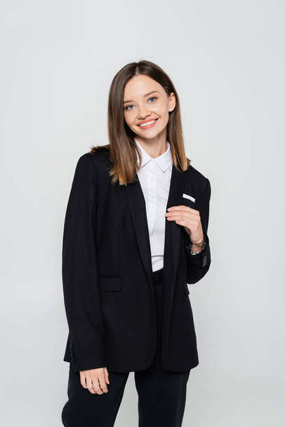 happy and stylish woman in suit smiling isolated on grey - Foto, Imagem