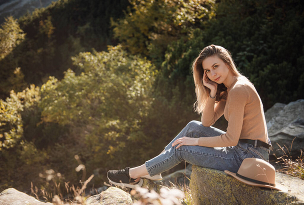 Молодая женщина туристка, сидящая на вершине горы и красивых гор. Пейзаж со спортивной девушкой, зеленый лес, холмы, небо, озеро. Путешествия и туризм. - Фото, изображение