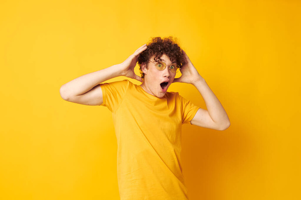 portrait of a young curly man wearing stylish glasses yellow t-shirt posing Lifestyle unaltered - Фото, изображение