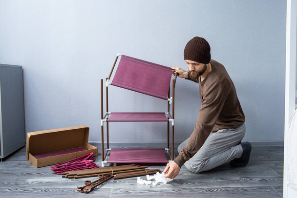 Bearded man assembles a shelf for the rack. - Photo, Image