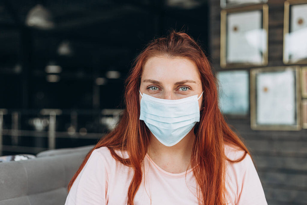 Una donna felice con una maschera protettiva medica sul viso si siede in aeroporto in attesa di un volo - Foto, immagini