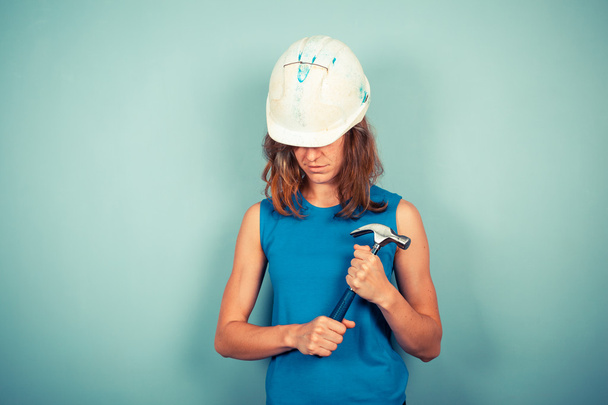 Young female builder with hammer - Foto, imagen