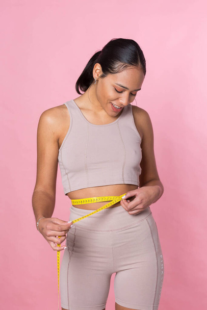 Young girl taking her measurements with a tape measure - Foto, imagen