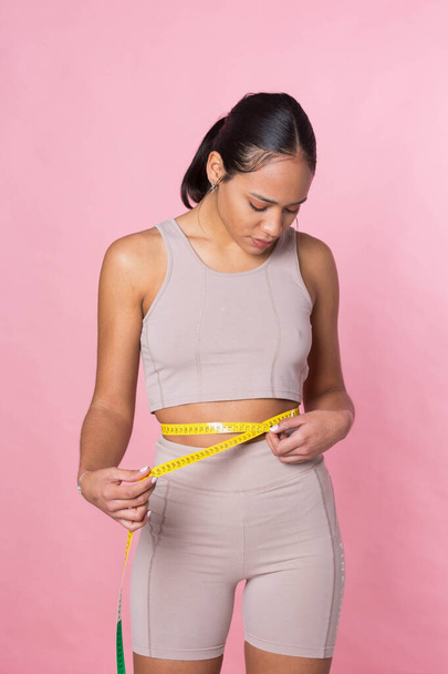 Young girl taking her measurements with a tape measure - Foto, Imagem