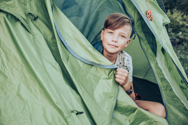Teenager boy sitting in camping tent. Family weekend outdoor. - Fotó, kép