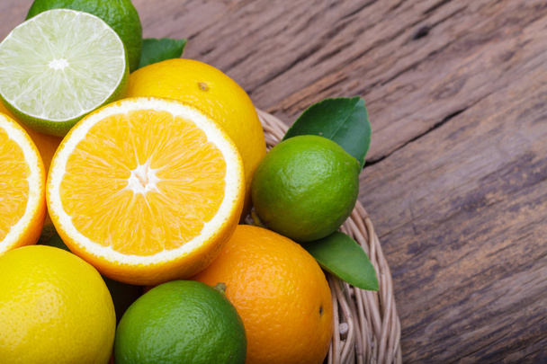 Mix of fresh citrus fruits in basket on  wood - Фото, зображення