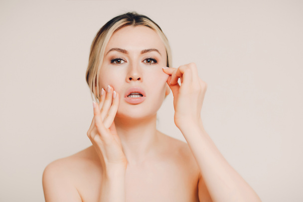 Young adult woman with nude makeup doing facial gymnastics and face skin self massage and rejuvenating exercises facebuilding and lifting. Smooth fresh skin and cosmetics concept - Photo, Image