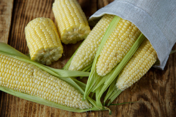 The young cobs of fresh yellow corn on the background of wooden table. Harvest from the organic garden. - Foto, Imagen