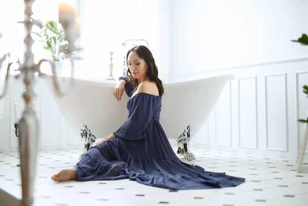 Gyönyörű fiatal nő kék ruhában pózol luxus fürdőszobában - Fotó, kép