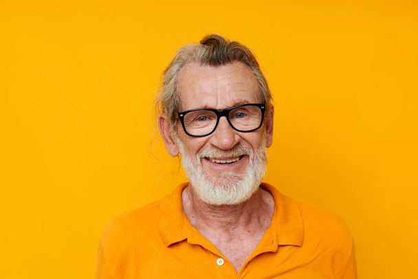 an elderly man with glasses in a yellow t-shirt with glasses close-up - Fotó, kép