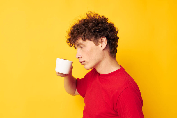 guy with red curly hair posing with a white mug and in the hands of a drink isolated background unaltered - Foto, Bild