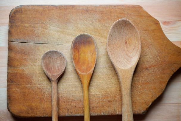 Wooden rustic spoons three pieces lie on a wooden cutting Board on the surface of the table. - Foto, immagini