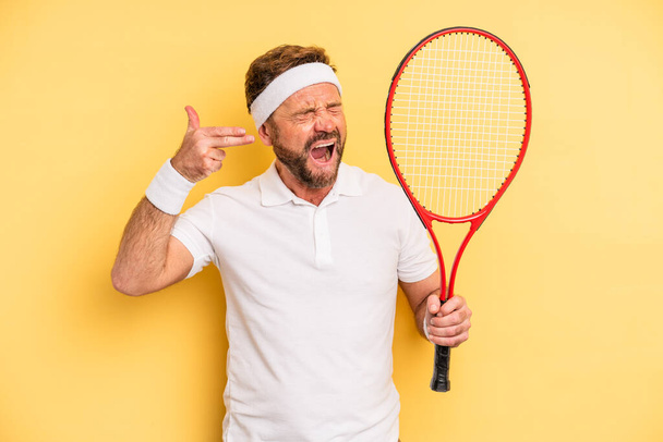 middle age man looking unhappy and stressed, suicide gesture making gun sign. tennis concept - Fotó, kép