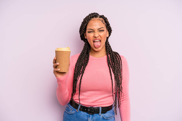 black afro woman with cheerful and rebellious attitude, joking and sticking tongue out. take away coffee - Фото, изображение