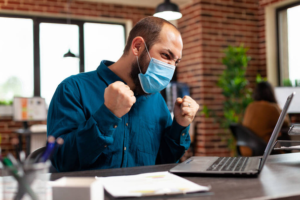 コロナウイルス感染を防ぐために医療保護面マスクを持つビジネスマン - 写真・画像