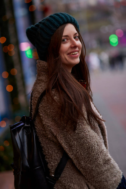 Lähikuva muotokuva kaunis nainen illalla kadulla lähellä koristeltu näyteikkuna. Talvi tyylikäs rento vaatteita. Kaupungin valot. Juhlakaupunki - Valokuva, kuva