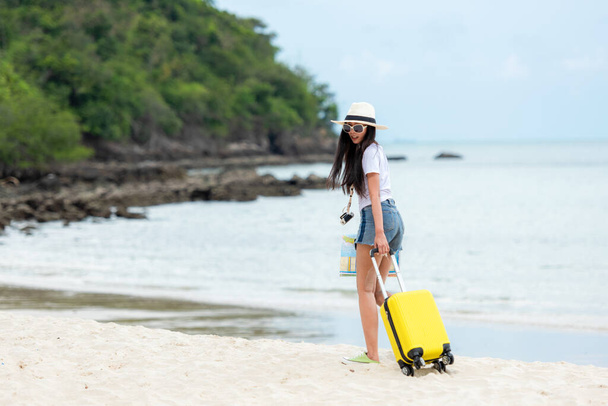 Happy traveler and tourism young women travel summer on the beach.  Asian people holding yellow suitcase, map and camera take photo and relax outdoor for destination and leisure trip travel in holiday - Foto, afbeelding