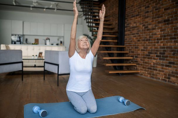 Gray-haired senior woman in sportswear doing stretching - Foto, imagen