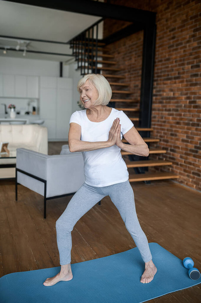 Slim aging woman doing yoga at home - Foto, afbeelding