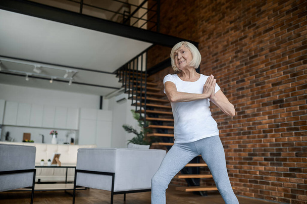 Slim aging woman doing yoga at home - Foto, afbeelding