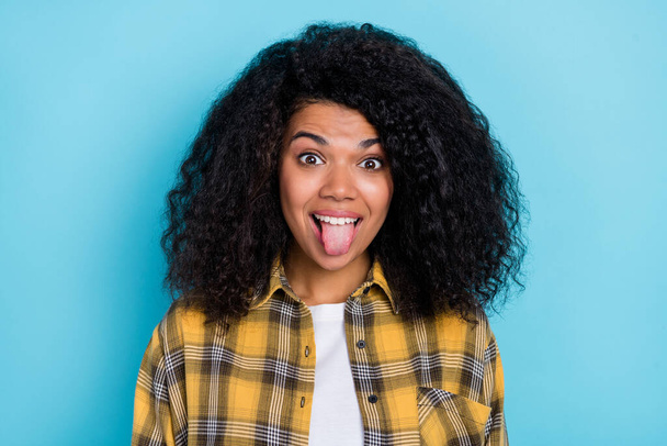 Photo of funny healthy pretty lady protrude tongue wear checkered shirt isolated blue color background. - Foto, immagini