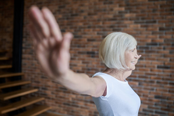 Короткошерста старша жінка стоїть з руками в сторони
 - Фото, зображення