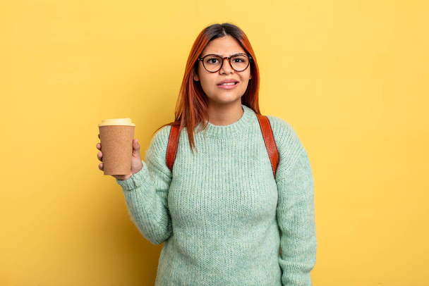 hispanic woman looking puzzled and confused. student with a coffee concept - Photo, image