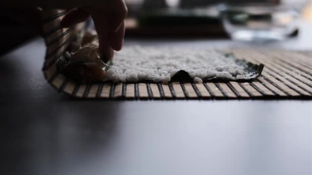  une femme prépare des rouleaux de sushi à la maison selon une classe de maître. une fille cuisine un plat japonais sushi rouleaux dans la cuisine sur une recette vidéo - Séquence, vidéo