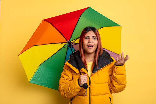 hispanic woman feeling happy, surprised realizing a solution or idea. rain and umbrella concept - Фото, зображення