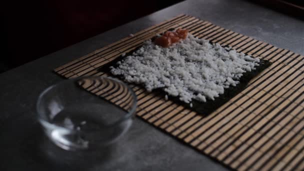 een vrouw bereidt sushi broodjes thuis volgens een masterclass. een meisje kookt een Japanse schotel sushi rollen in de keuken op een video recept - Video