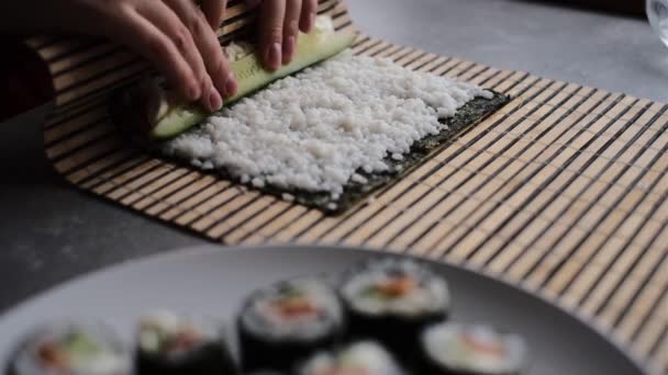  een vrouw bereidt sushi broodjes thuis volgens een masterclass. een meisje kookt een Japanse schotel sushi rollen in de keuken op een video recept - Video