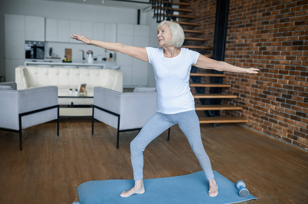 A senior woman standing in a warrior pose - Photo, Image