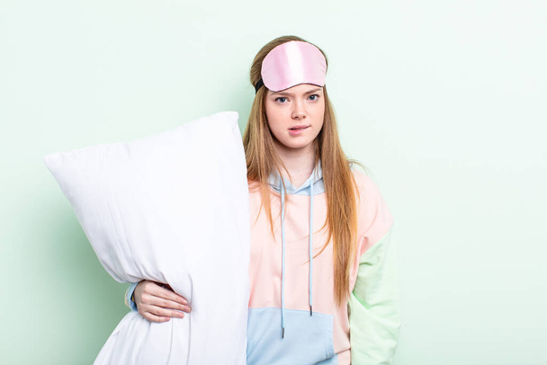 redhair woman looking puzzled and confused. pajamas and pillow concept - Photo, image