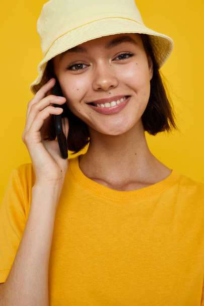 young beautiful woman yellow t-shirt and Hat summer style with phone Lifestyle unaltered - Foto, imagen