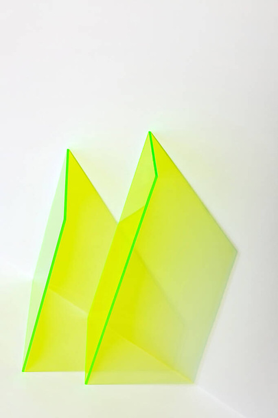 Neon yellow acrylic shapes on a bright lit white background. Colourful minimalist stage for advertising, promoting, exhibition new products. Stylish abstract backdrop with space for text.  - 写真・画像
