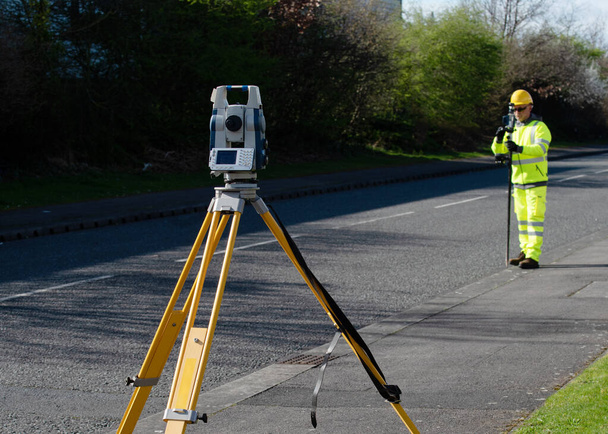 Site engineer doing road survey using modern robotic total station EDM before begining of construction works and setting construction site - Fotoğraf, Görsel