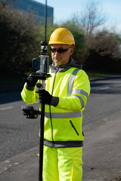 Site engineer doing road survey using modern robotic total station EDM before begining of construction works and setting construction site - Foto, Imagem