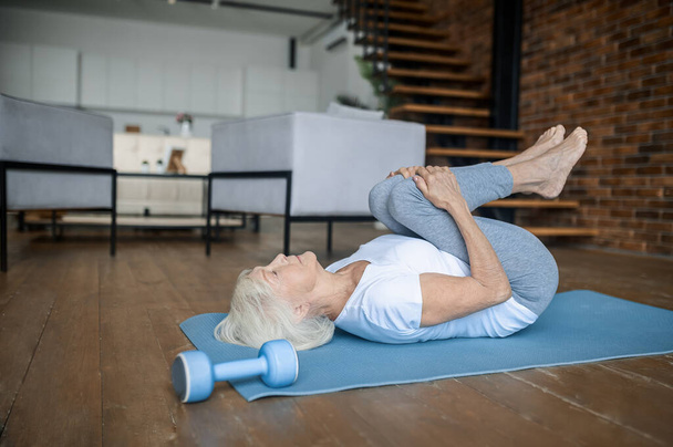 An elderly lady doing yoga at home - Foto, Bild