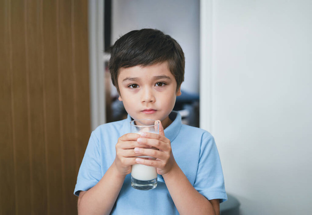 Ritratto ragazzo della scuola sano bere un bicchiere di latte per la prima colazione, Bambino felice in piedi in cucina bere latte caldo prima di andare a scuola. Concetto di Healhty food liftstyle - Foto, immagini