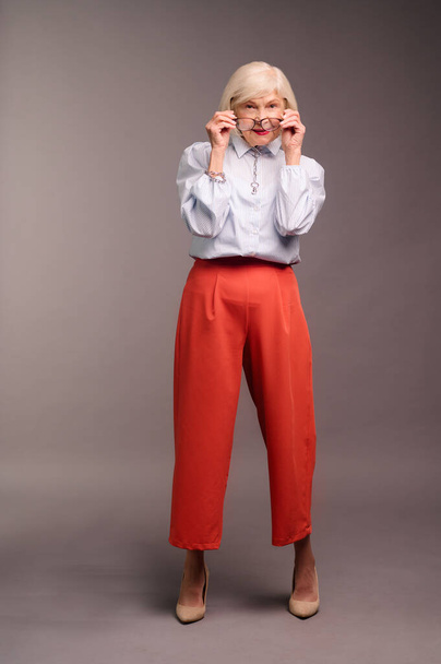Elegant senior woman in white blouse and red pants - Photo, Image