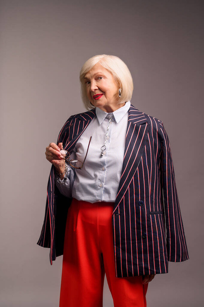 Blonde senior elegant woman in red pants and stylish jacket - Фото, изображение