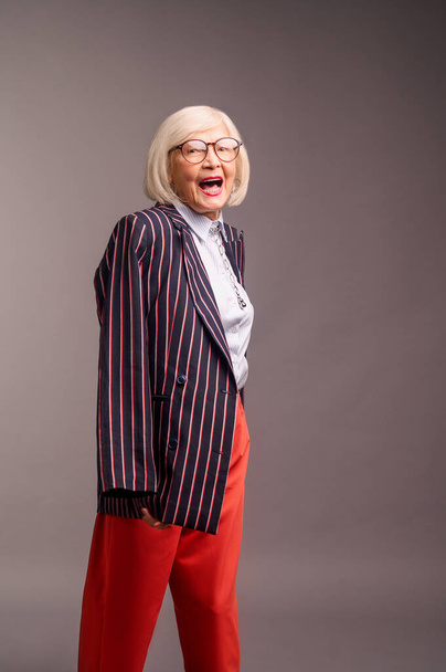 Blonde senior elegant woman in red pants and stylish jacket - Photo, image